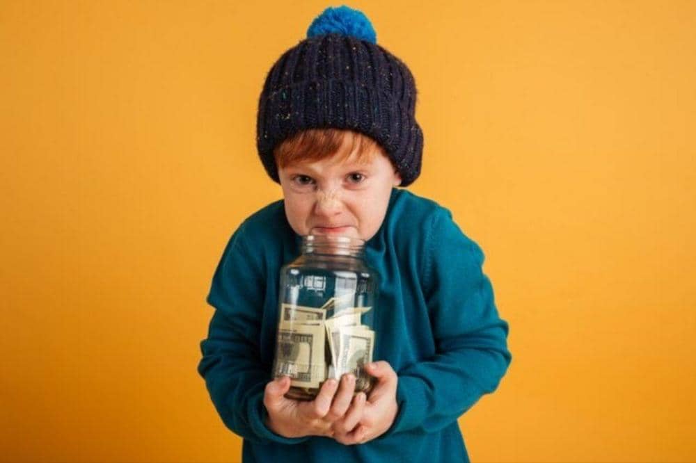 Si Kecil memegang toples berisi uang