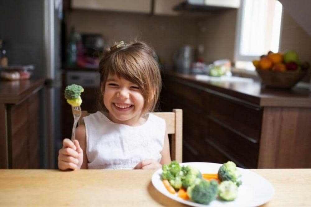 Anak perempuan memegang brokoli