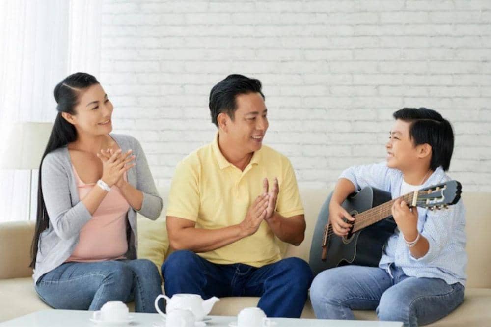 Anak remaja bermain gitar di depan Mama dan Papa