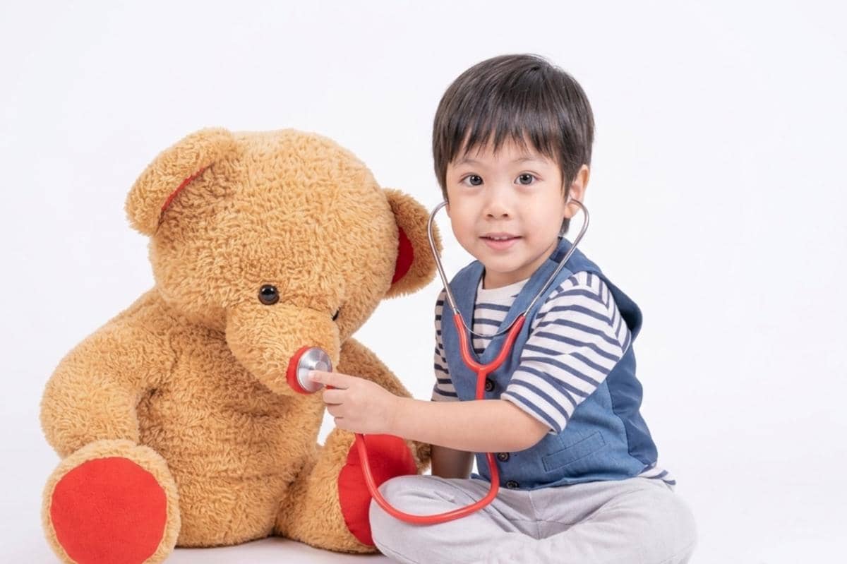anak laki-laki sedang bermain dengan boneka beruang