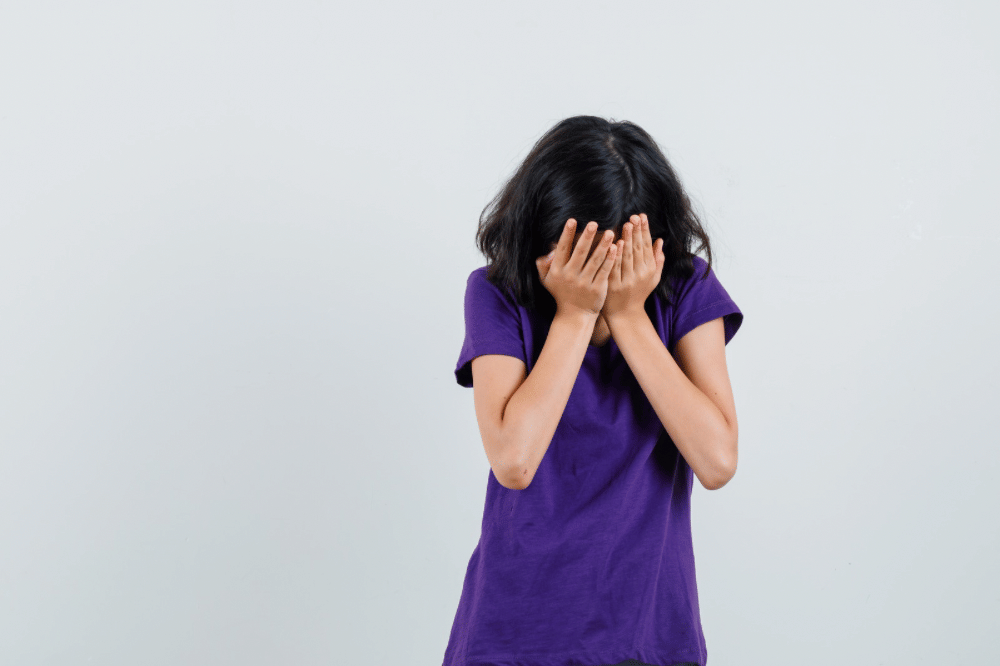 Anak perempuan bersedih dan menutupi wajahnya dengan tangan