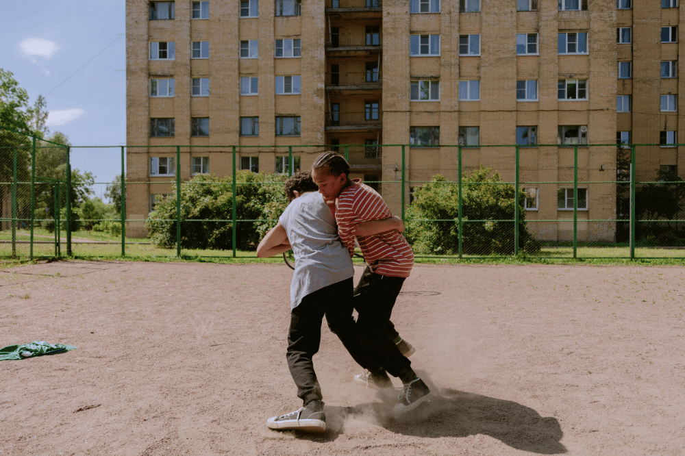 Dua remaja laki-laki sedang bertengkar di lapangan