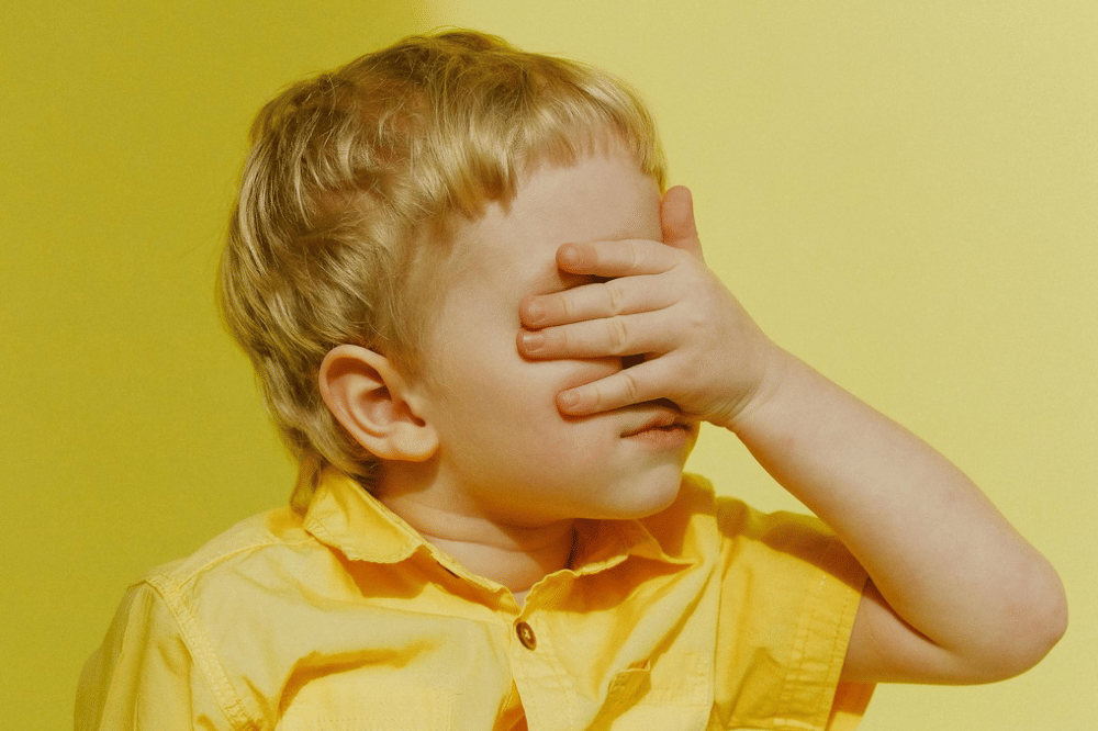 Anak sedang malu dan menutupi matanya dengan tangan
