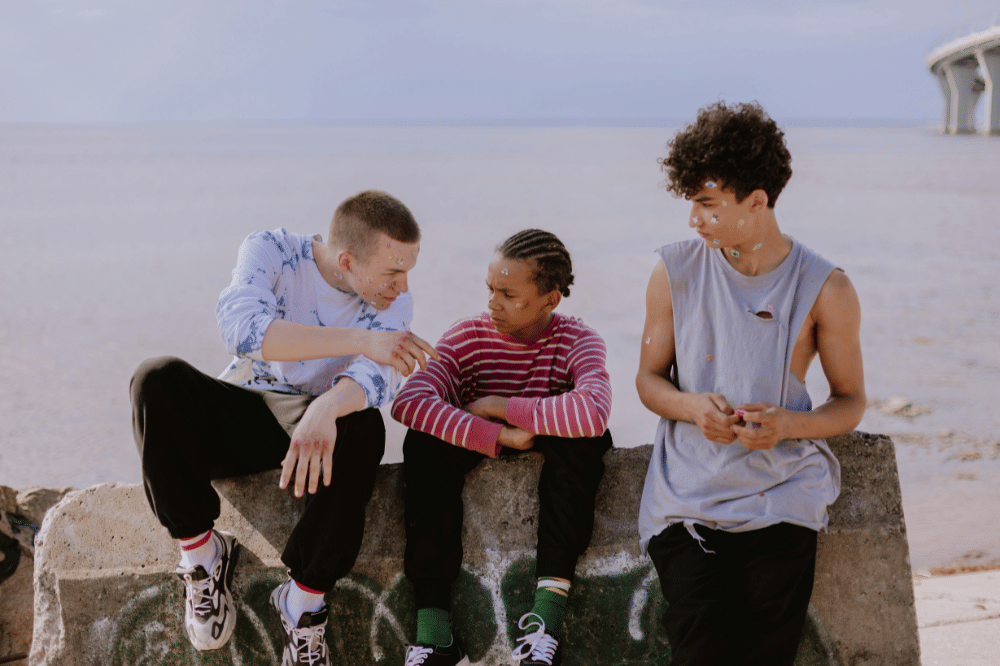 Tiga remaja laki-laki sedang berinterkasi di pinggir sungai