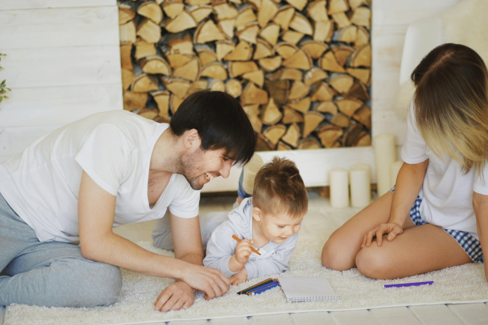 Ayah, anak dan Ibu sedang menghabiskan waktu di ruang tamu sambil menggambar 