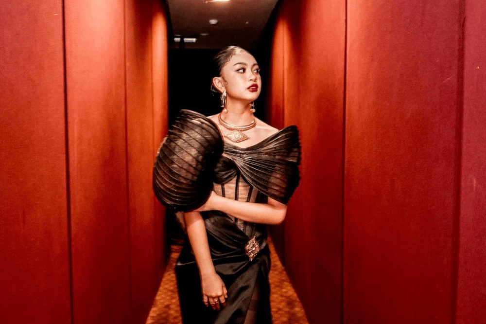 Zara Leola berpose mengenakan gaun hitam dengan latar merah 