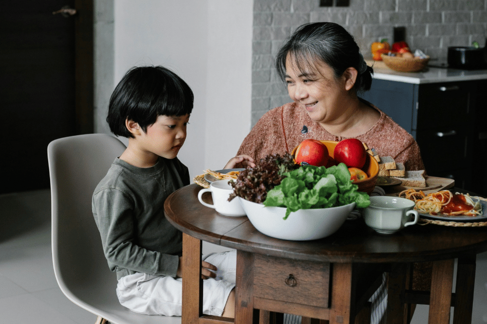 Seorang nenek dan cucuk laki-lakinya sedang berbincang di meja makan