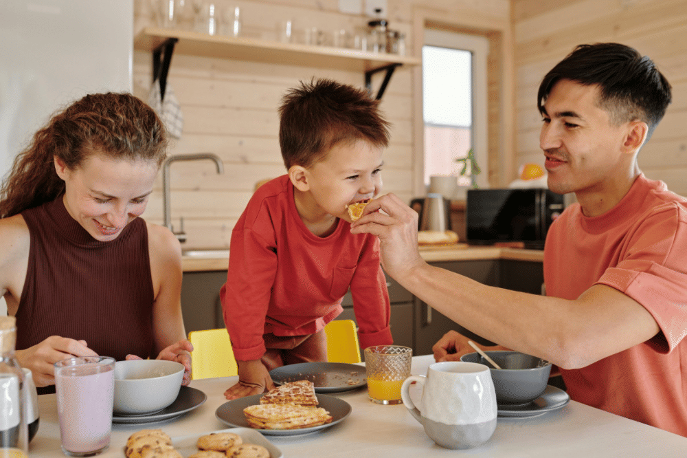 Papa, Mama dan anak laki lakinya sedang makan waffle di meja makan