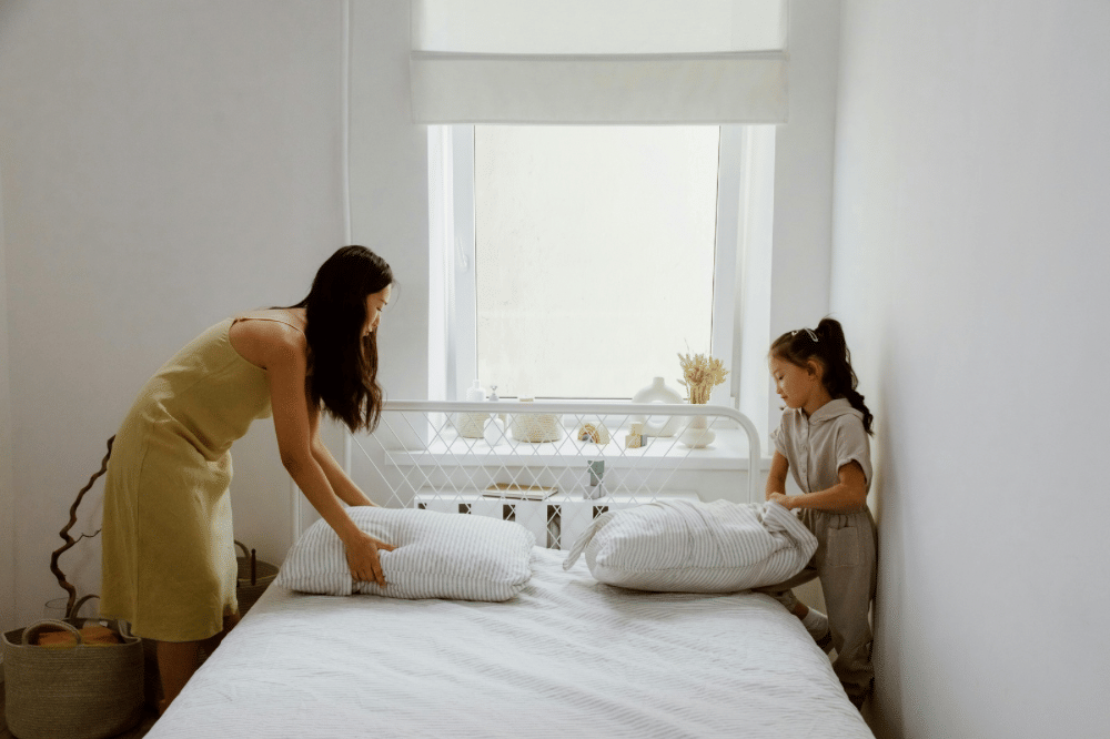 Mama dan anak perempuannya sedang merapihkan kasur