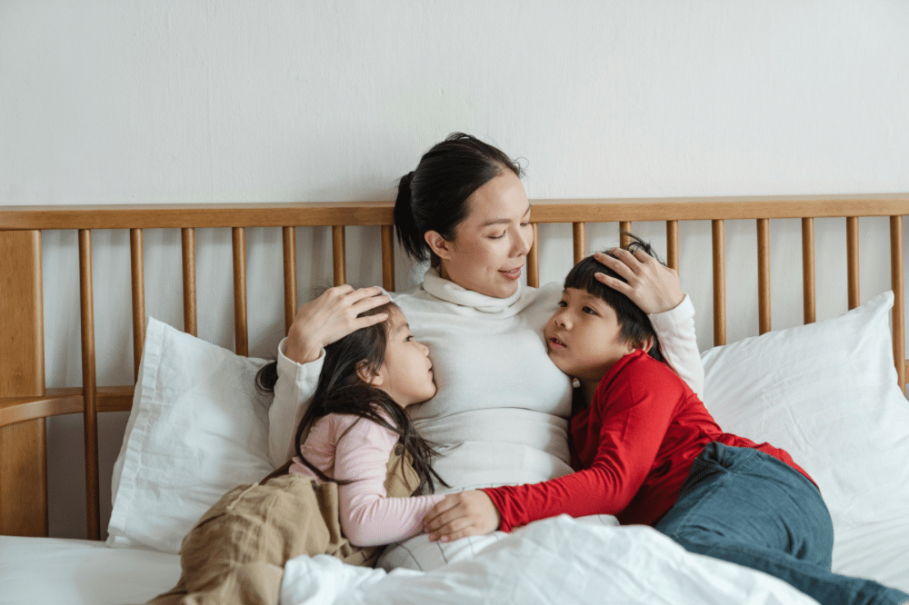mama dan kedua anaknya sedang bercengkrama di tempat tidur