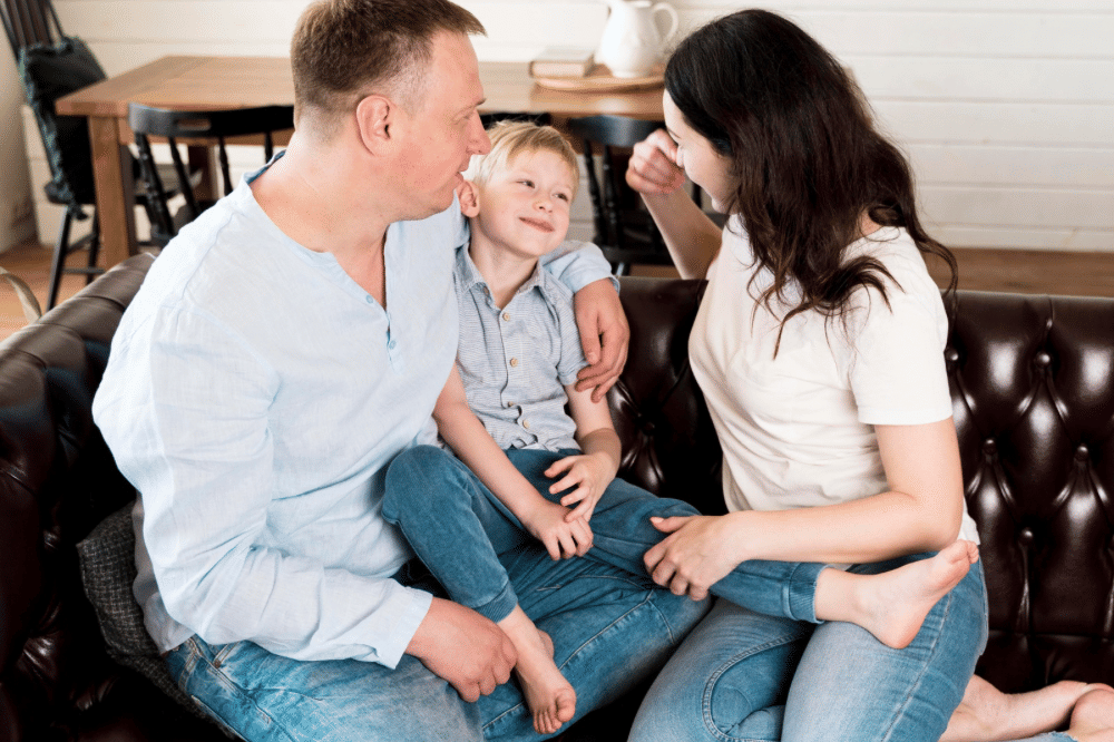 Mama, papa, dan anak laki-lakinya bercengkrama di sofa