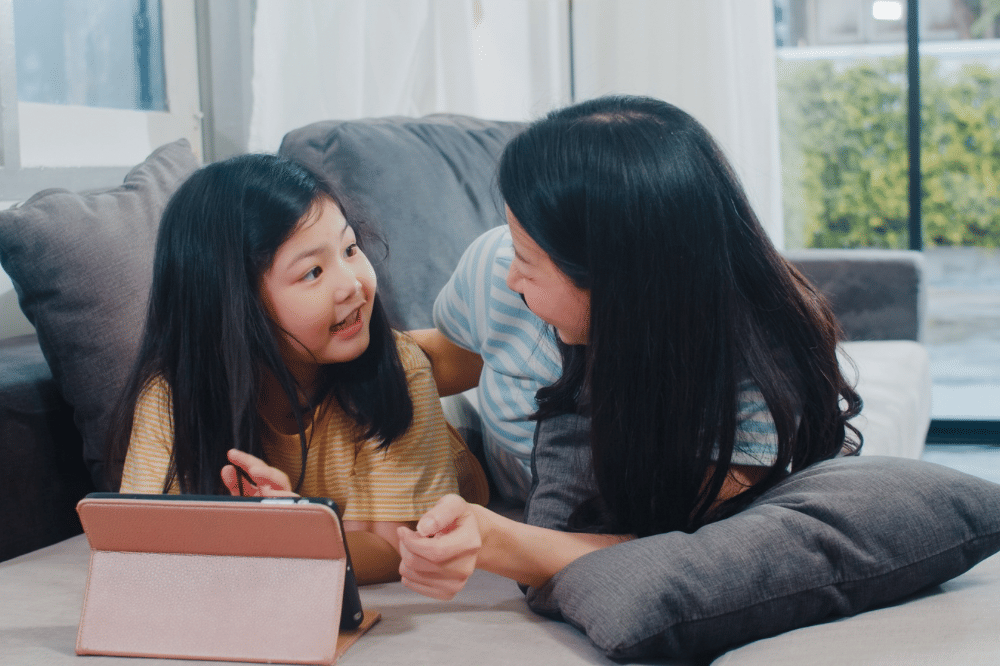 mama dan anak perempuannya berbincang sembari bermain tablet
