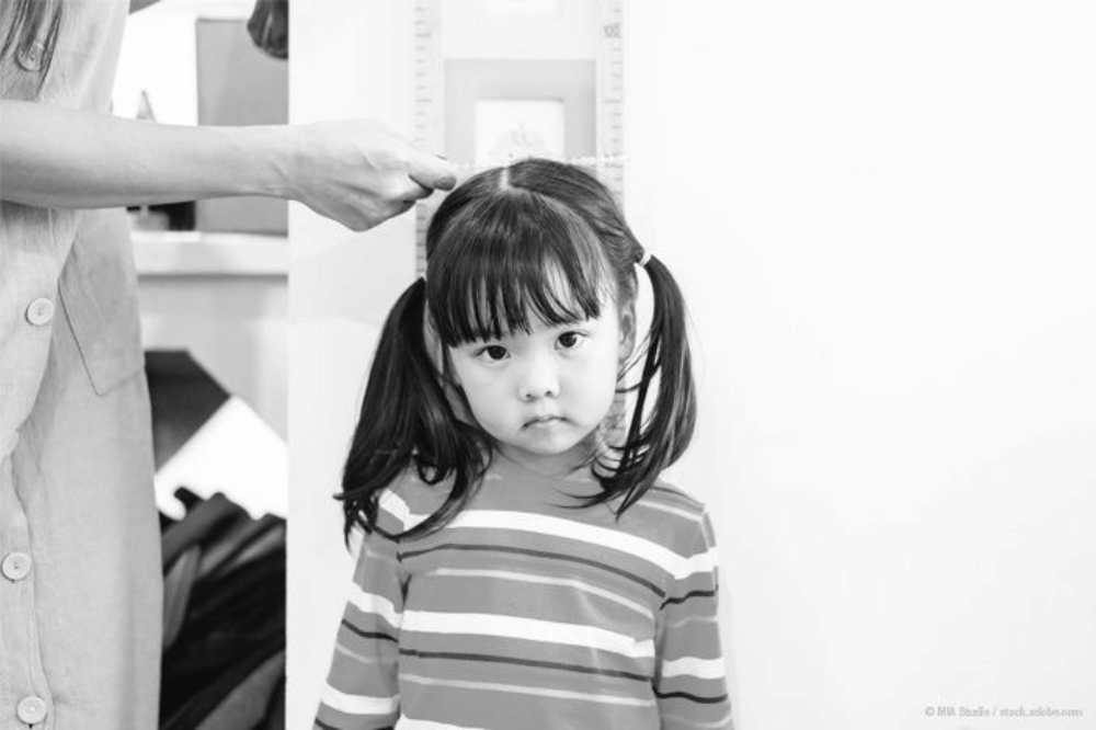 seorang anak perempuan sedang diukur tinggi badannya