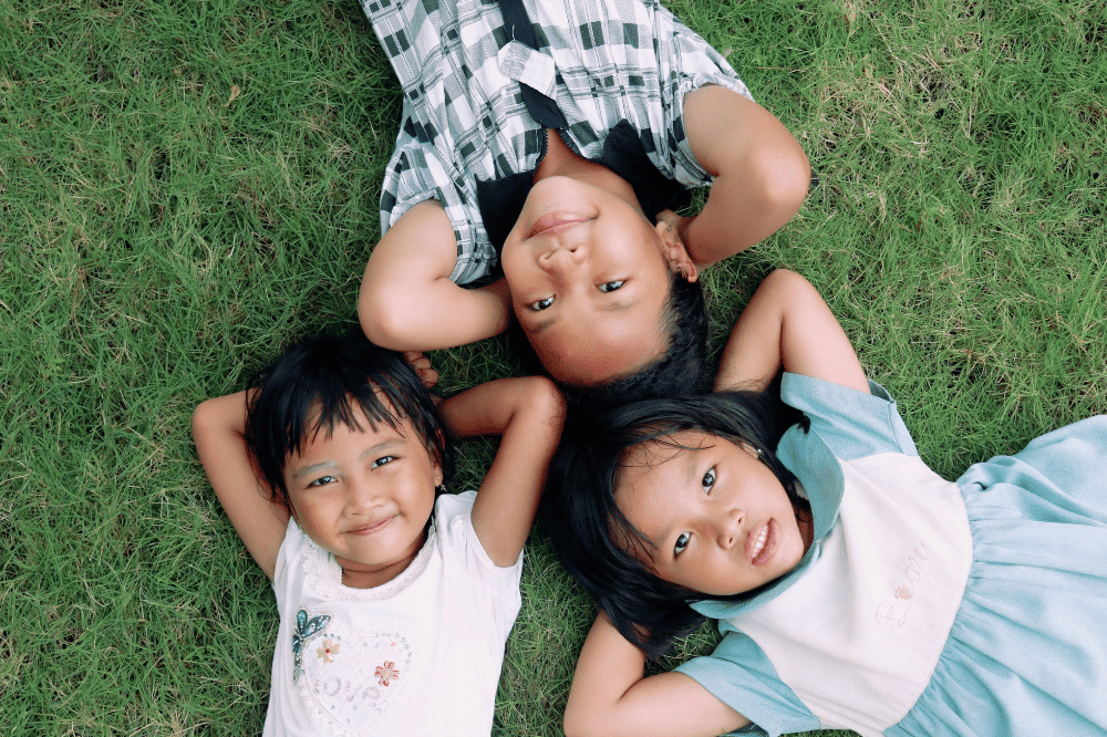 Tiga anak perempuan berbaring di rumput 
