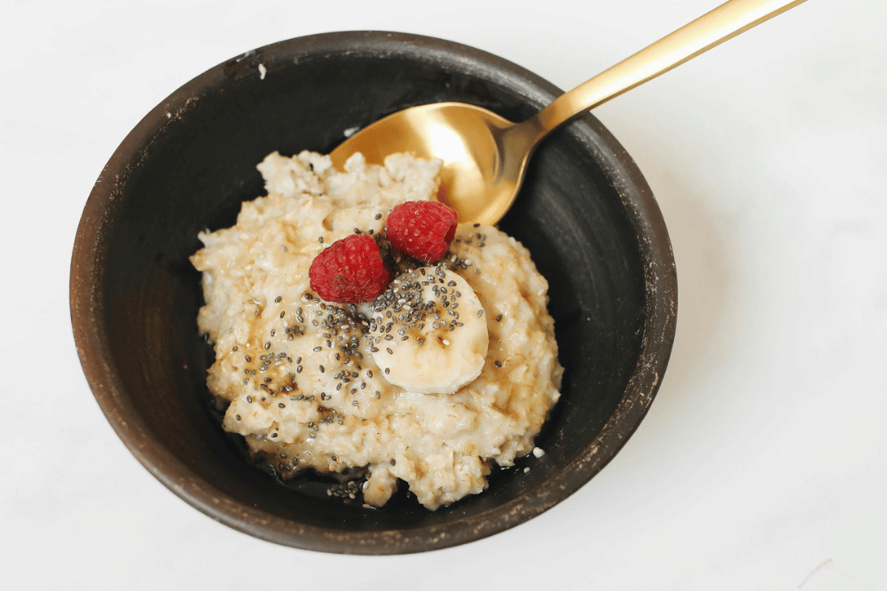 semangkuk oat dengan topping pisang dan raspberry