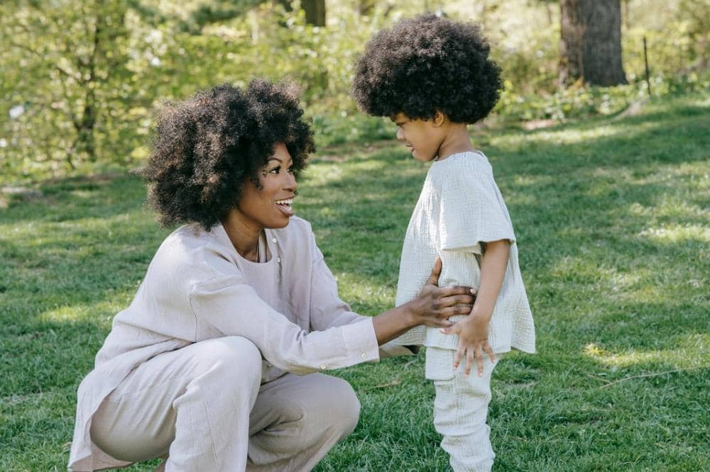 Mama berjongkok sambil tersenyum kepada anak 