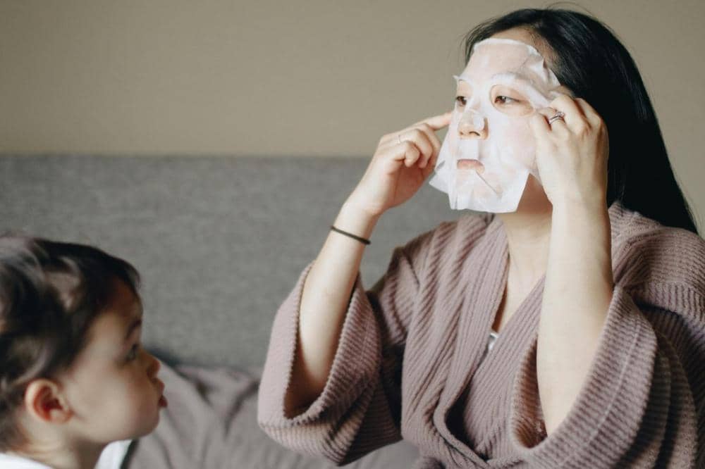 Mama mengenakan masker wajah sambil duduk di sofa