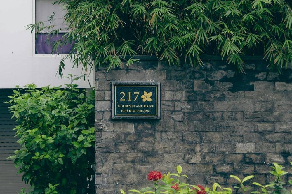 Papan alamat bertuliskan 217 Golden Flame Drive di dinding batu abu-abu