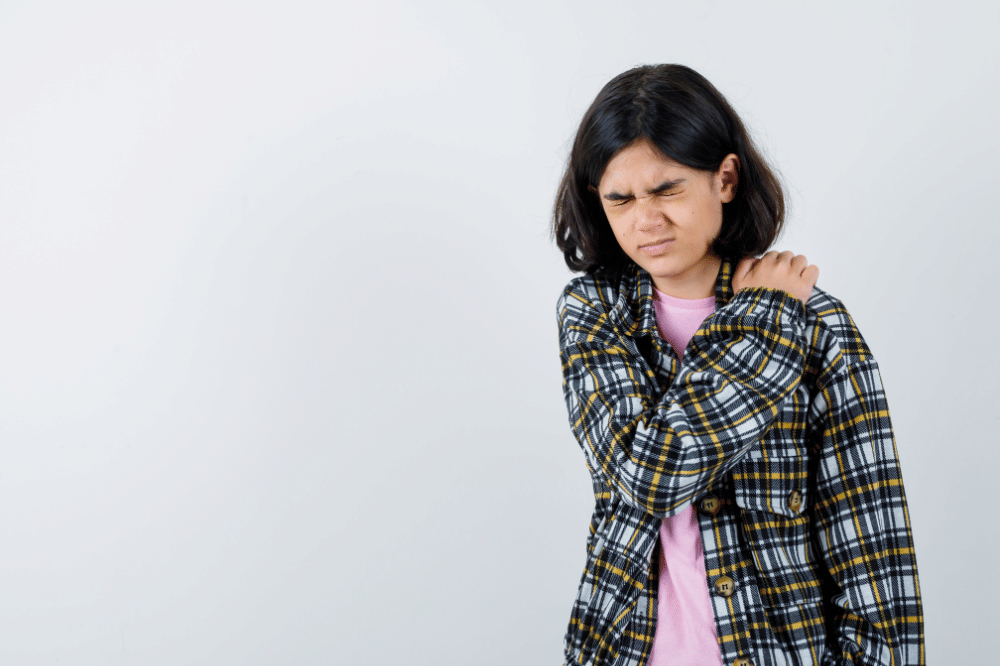 Seorang perempuan memegangi bahu sambil menahan rasa sakit