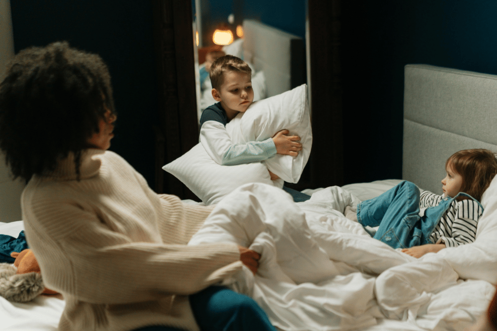 Seorang wanita duduk di tempat tidur bersama dua anak kecil