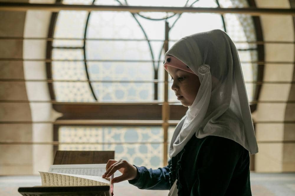 Seorang anak perempuan berhijab membaca Al-Qur'an