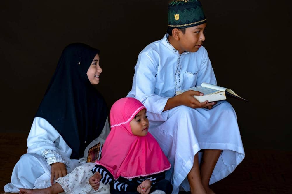 Tiga anak mengenakan busana muslim