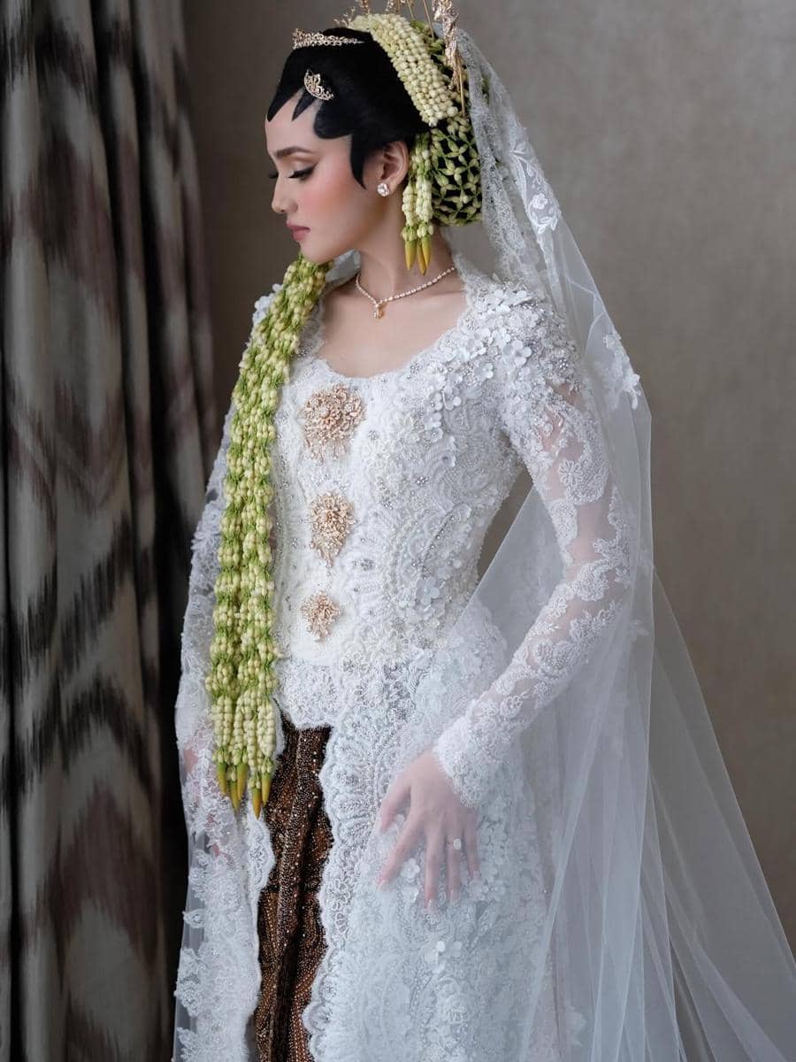 Syifa Hadju mengenakan kebaya putih berhias renda dan melati panjang di sanggul, dengan riasan tradisional Jawa yang anggun.