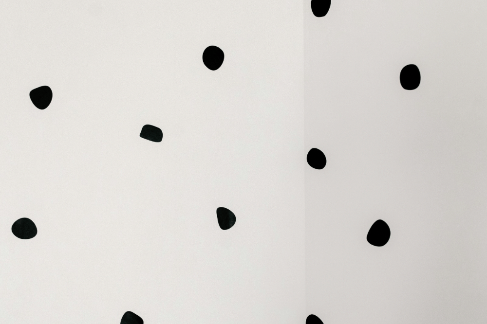 Dinding berwarna putih dengan pola titik-titik hitam acak