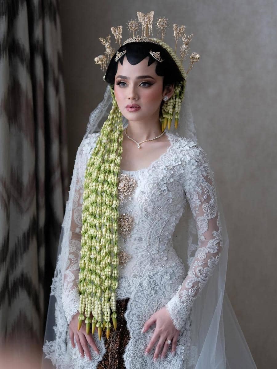 Syifa Hadju mengenakan kebaya pengantin putih berhias payet dengan sanggul tradisional Jawa dan ronce melati panjang di bahu