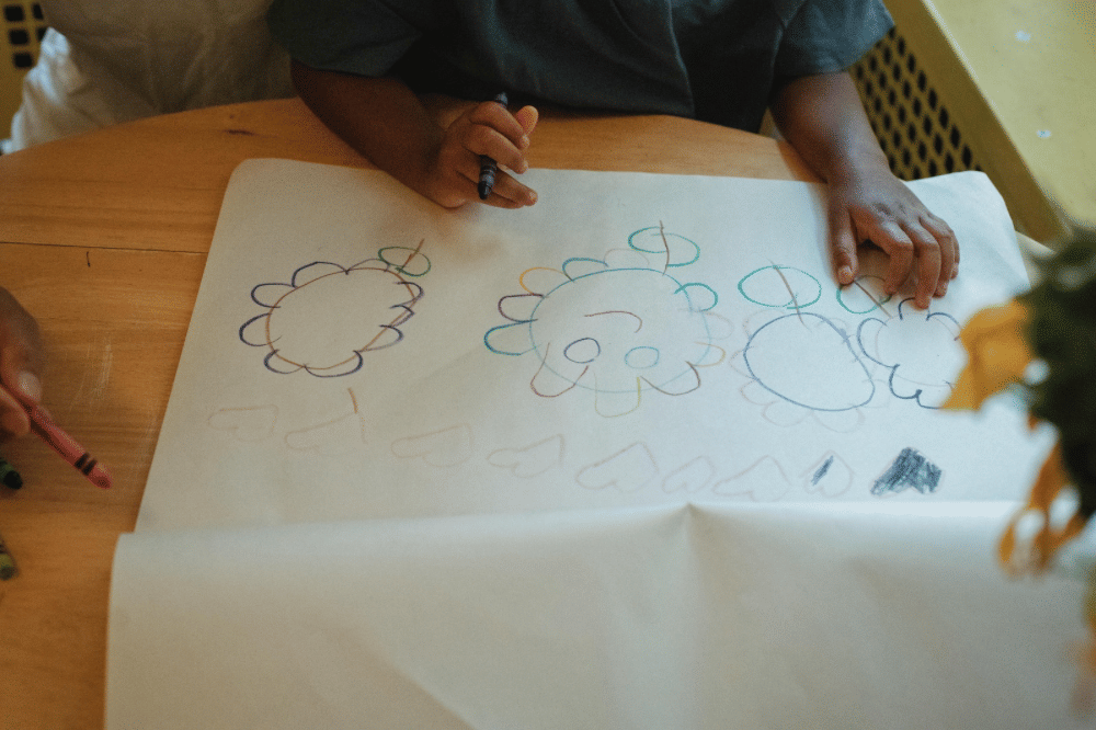 seorang anak sedang menggambar di kertas 