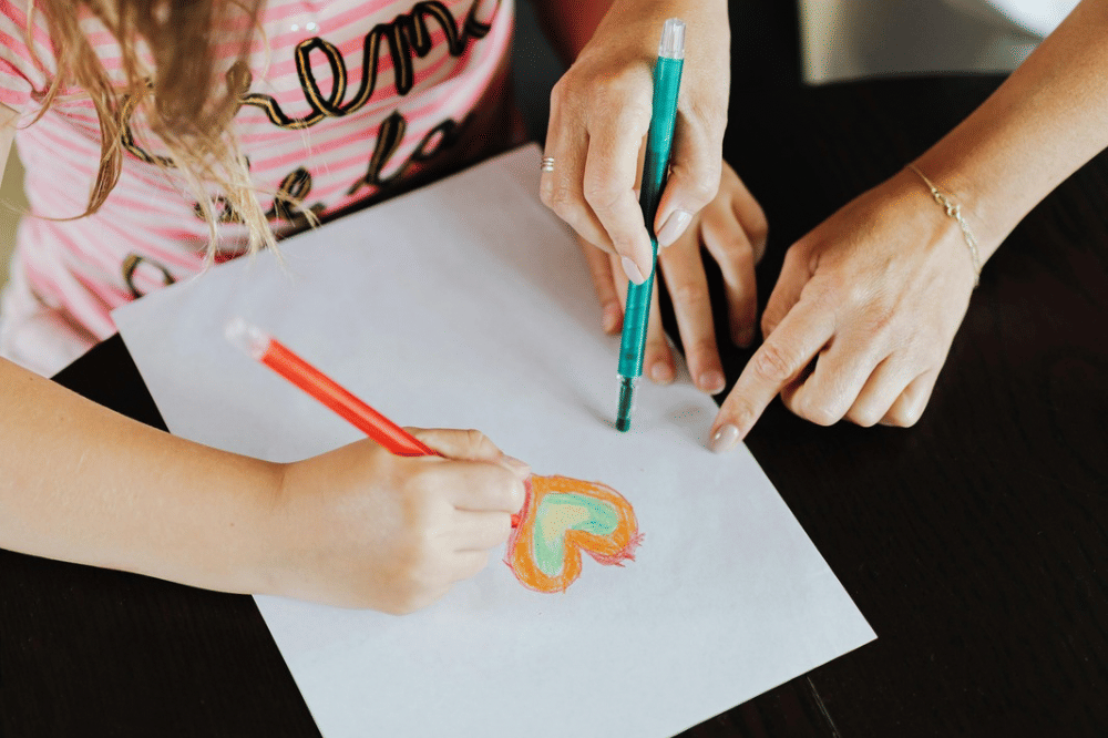 anak perempuan dan mama sedang menggambar di atas kertas 