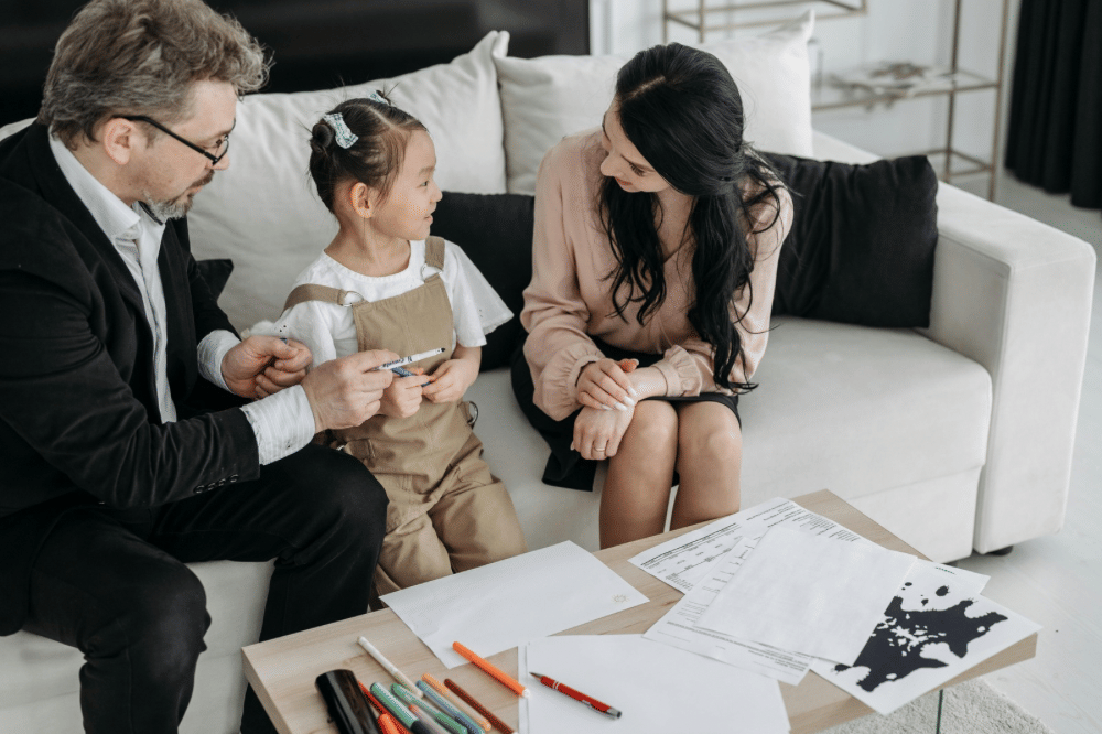 Papa, mama, dan anak perempuannya bercengkrama di sofa 