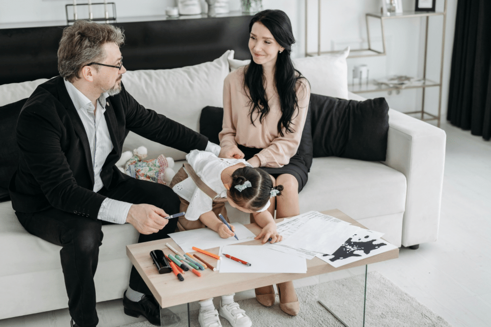 papa, mama, dan anak perempuanna sedang bercengkrama di ruang tamu