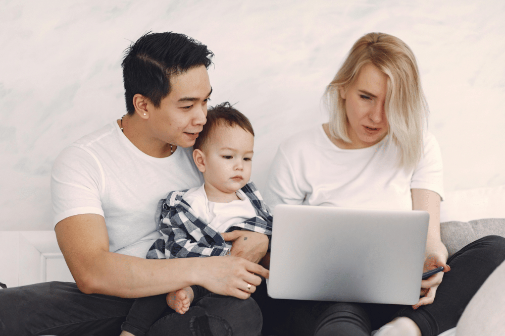 Papa, mama, dan anak sedang memperhatikan layar laptop