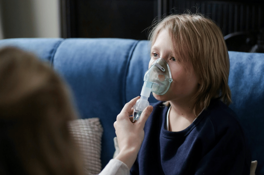 Seorang anak laki-laki yang sedang menggunakan alat nabulizer