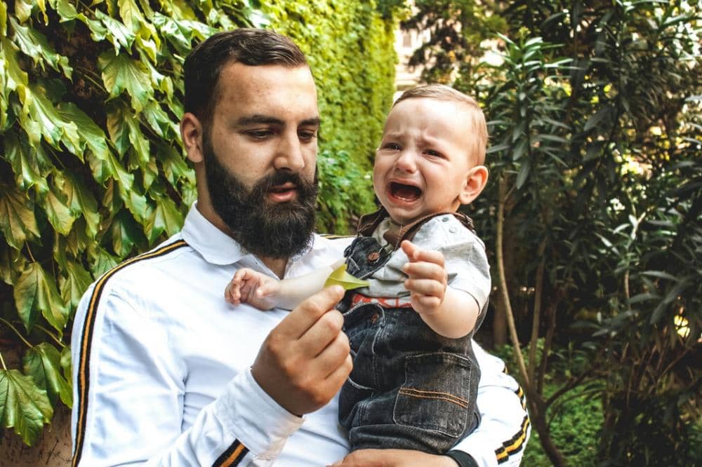 Anak sedang menangis sambil digendong Papa