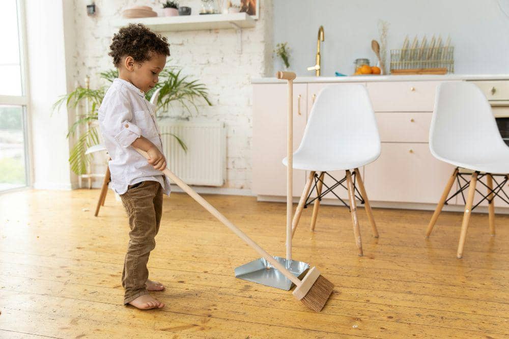 Anak laki-laki sedang menyapu lantai