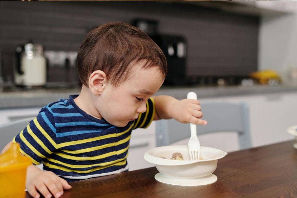 Anak laki-laki sedang makan sendiri