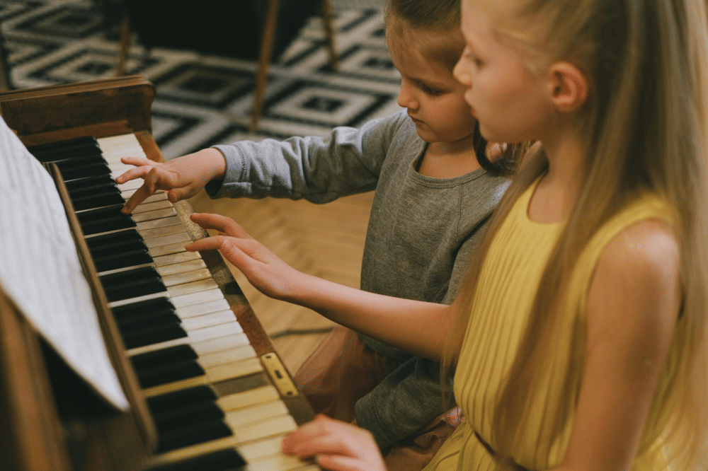 Dua saudara perempuanpuan bermain piano bersama 