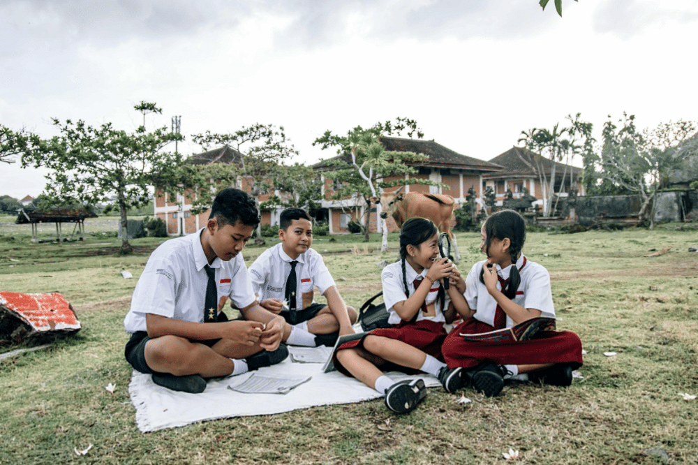 Anak anak sekolah sedang duduk bersama 