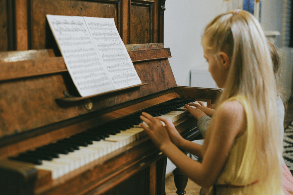 Dua orang anak perempuan bermain piano bersama 