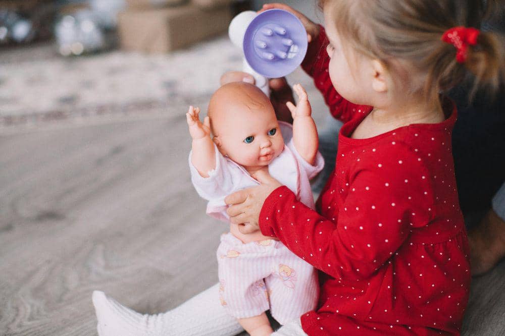 Anak perempuan menggendong boneka bayi