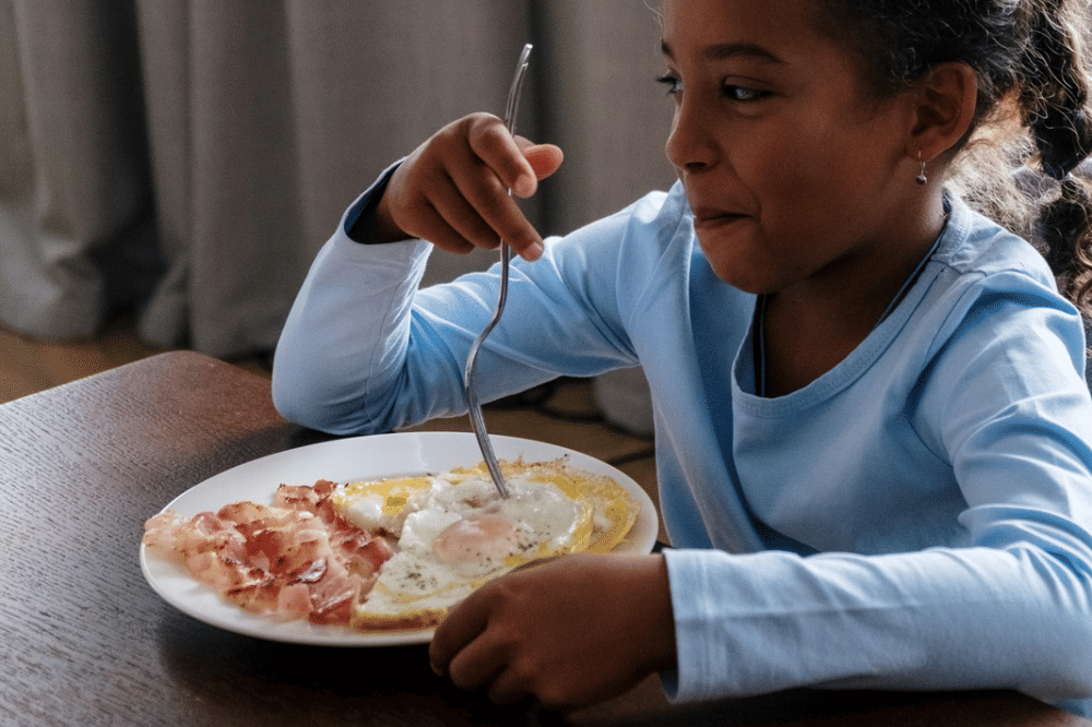 Seorang anak perempuan sedang makan telur