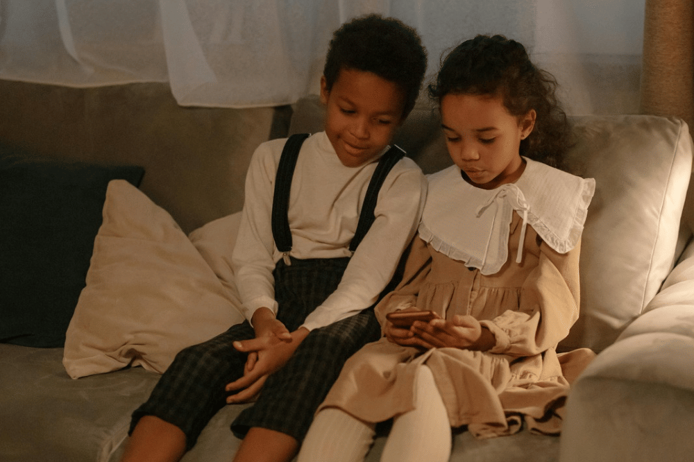 Dua orang anak sedang bermain handphone