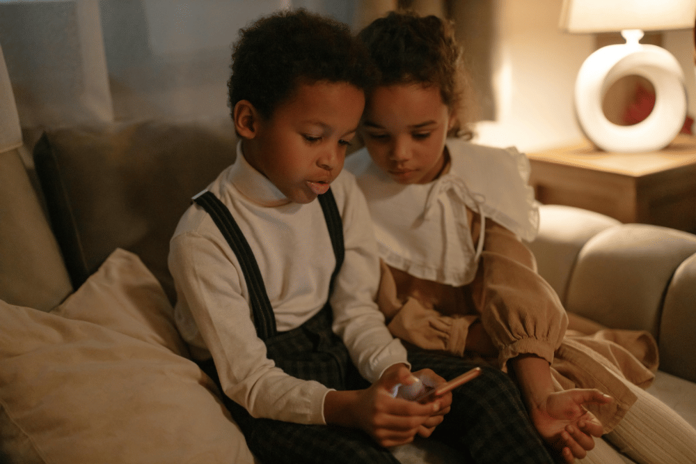 dua orang anak sedang bermain handphone