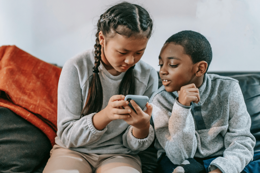 dua orang anak sedang melihat layar handphone