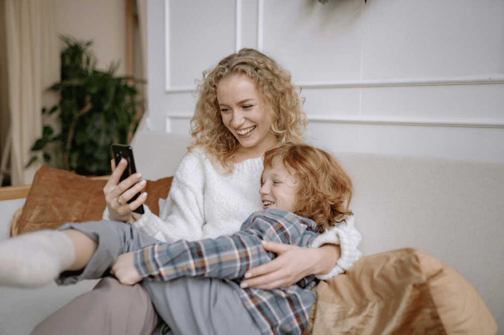 mama dan anaknya sedang bermain handphone 