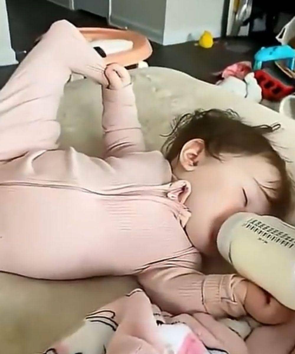 Tidur telentang sambil memegang kaki dan botol susu