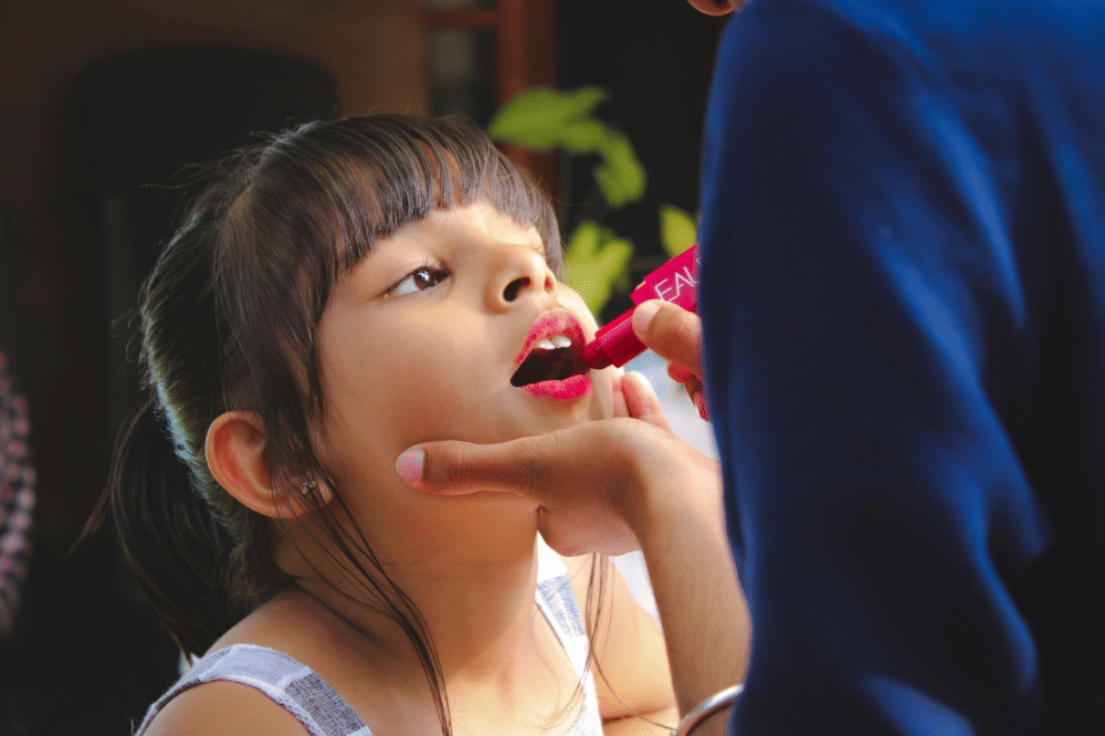 seorang anak perempuan sedang mengenakan lipstick
