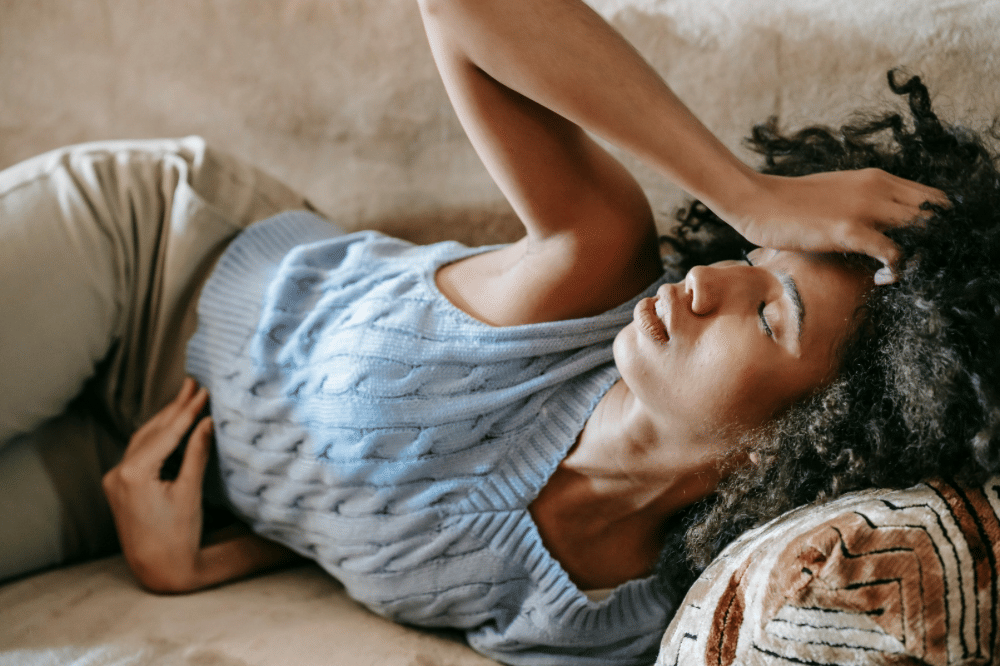 seorang perempuan kesakitan sembari memegang perut dan kepalanya 
